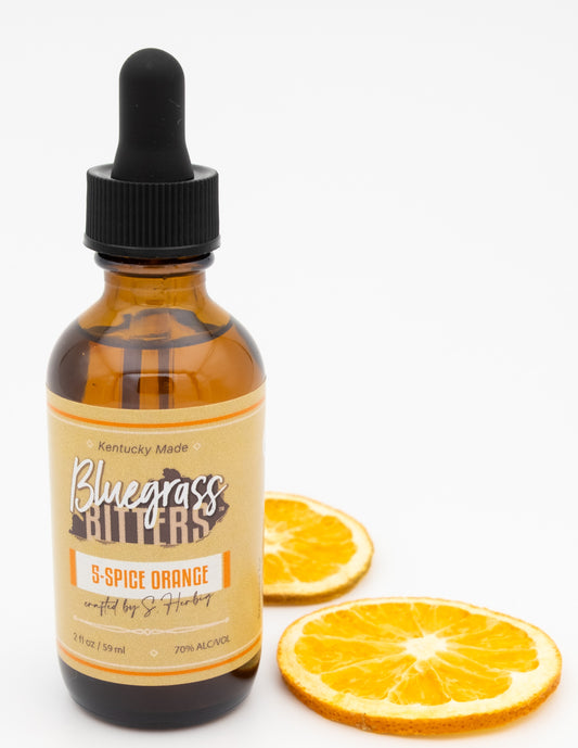 Bottle of Bluegrass Bitters with a dropper on a white background with orange slices.
