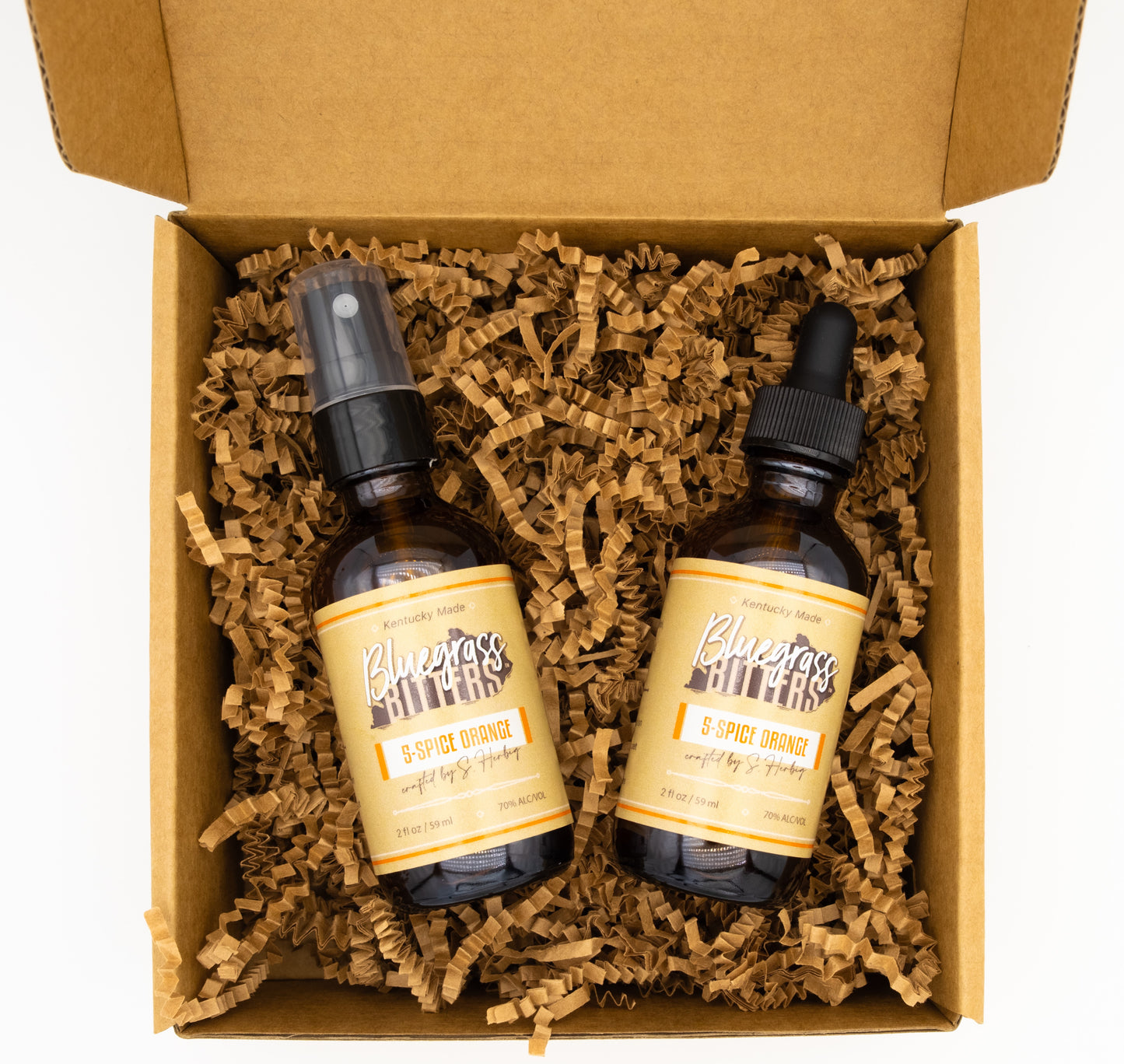 Two bottles with labels in a box with brown crinkle paper