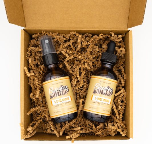 Two bottles with labels in a box with brown crinkle paper
